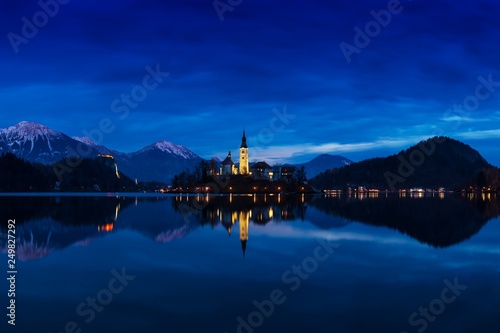 Beautiful view of famous Bled Island (Blejski otok) at scenic Lake Bled with Bled Castle (Blejski grad) and Julian Alps in the background in golden morning light at sunrise in summer, Slovenia 