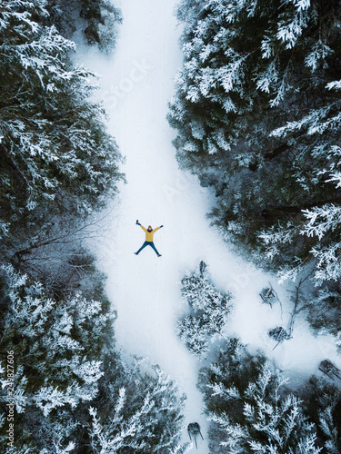 Aerial view of the lying man in winter forest in mountains