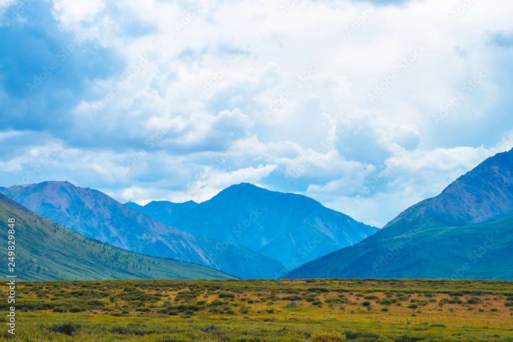 Spectacular view of giant mountains under cloudy sky. Huge mountain range at overcast weather. Wonderful wild scenery. Atmospheric dramatic highland landscape of majestic nature. Scenic mountainscape.