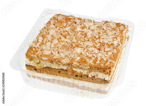 Biscuit honey cake with condensed sweet milk cream and nuts in plastic box isolated