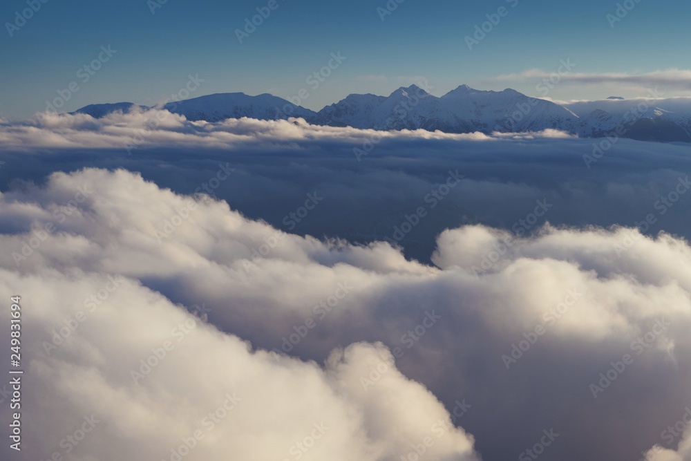 Panoramic view of beautiful winter wonderland mountain scenery in evening light at sunset. Mountains above the clouds. View of the High Tatras peaks. Slovakia. Christmas time, Happy New year concept
