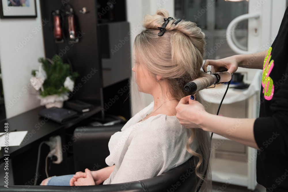 Professional hairdresser makes curls using curling Professional hairdresser makes curls using curling
