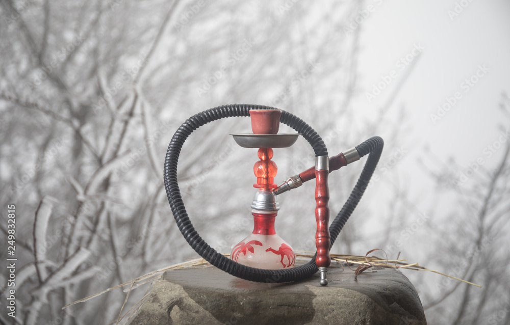 Hookah, traditional arabic waterpipe, direct sunset light, outdoor photo. Mountain background. Outdoor. Empty space.