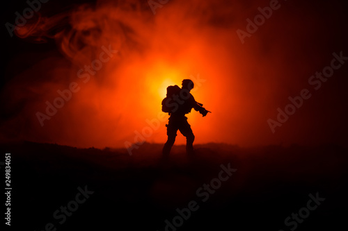 Military soldier silhouette with gun. War Concept. Military silhouettes fighting scene on war fog sky background, World War Soldier Silhouette Below Cloudy Skyline At night.