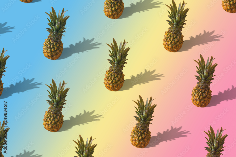 Fototapeta premium Neon pineapple fruits pattern on pink and blue background. Summer concept