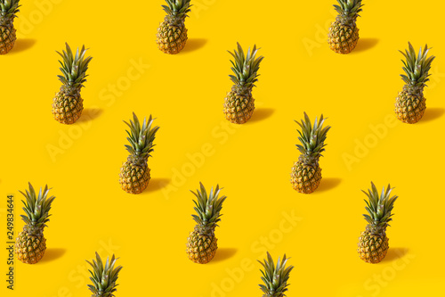Summer colorful fruit minimal pattern of fresh pineapples on yellow backgroun...