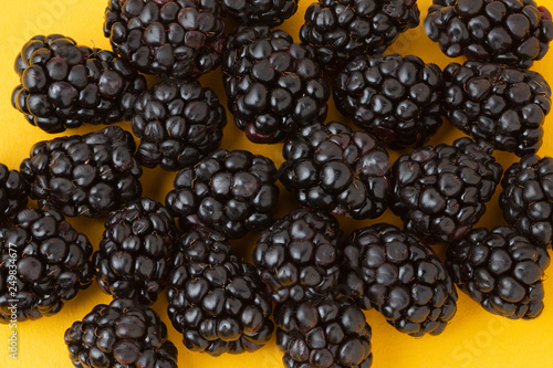 Blackberries on yellow background close-up. Top view. Flat lay