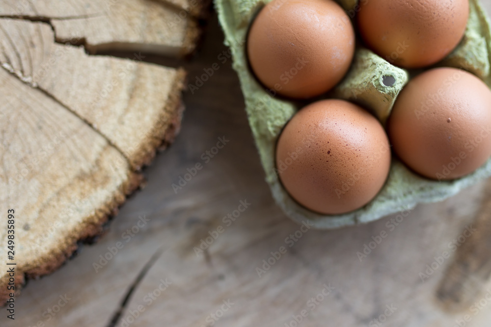 Closeup of raw chicken eggs in egg box on brown wooden background Closeup of raw chicken eggs in egg box on brown wooden background