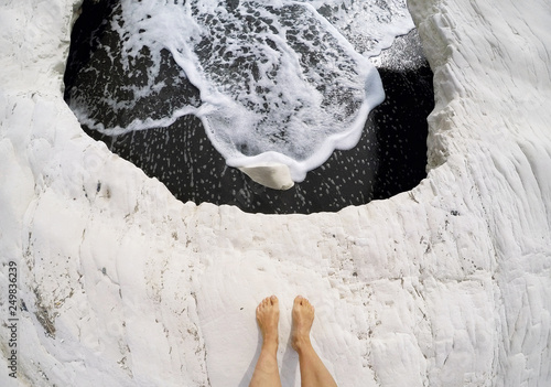 Woman feet on white rock on famous Governor's beach with black sand, landmark of Cyprus photo