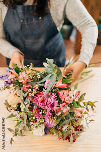 Fotografie Woman florist makes flowers bouquet  and wrapping in pack paper