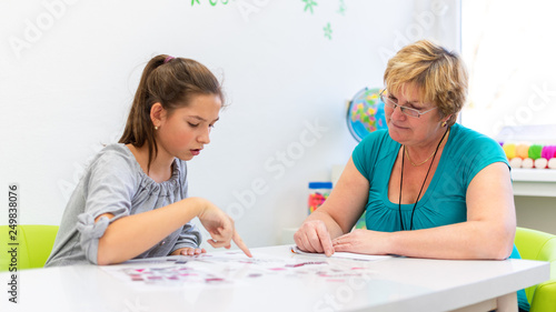 Mature female therapist working with a teenage girl with learning difficulties to master logical tests. photo