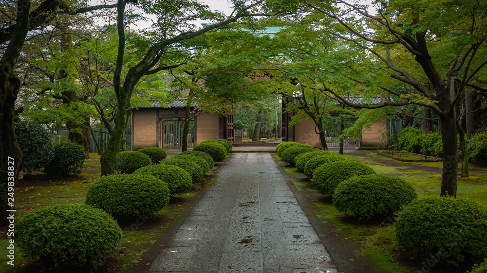 Landscape photo of the grounds of Gotokuji Temple in Tokyo right in front of the entrance gate which are very beautiful, with the well-tended gardens and a peaceful atmosphere. 