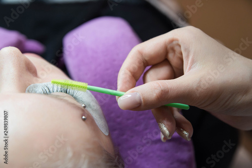 Beauty and fashion concept - Eye lash extension procedure. Young beautiful woman eye with long false eyelashes. Close up macro shot of fashion eyes in beauty salon.