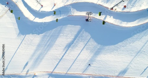 Aerial top view of ski area with marks and working chairlifts. Skiers and snowboarders moving down the hill