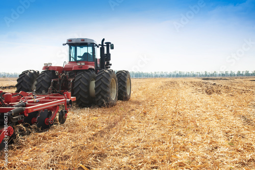 The tractor plows the field, cultivates the soil for sowing grain. The concept of agriculture.