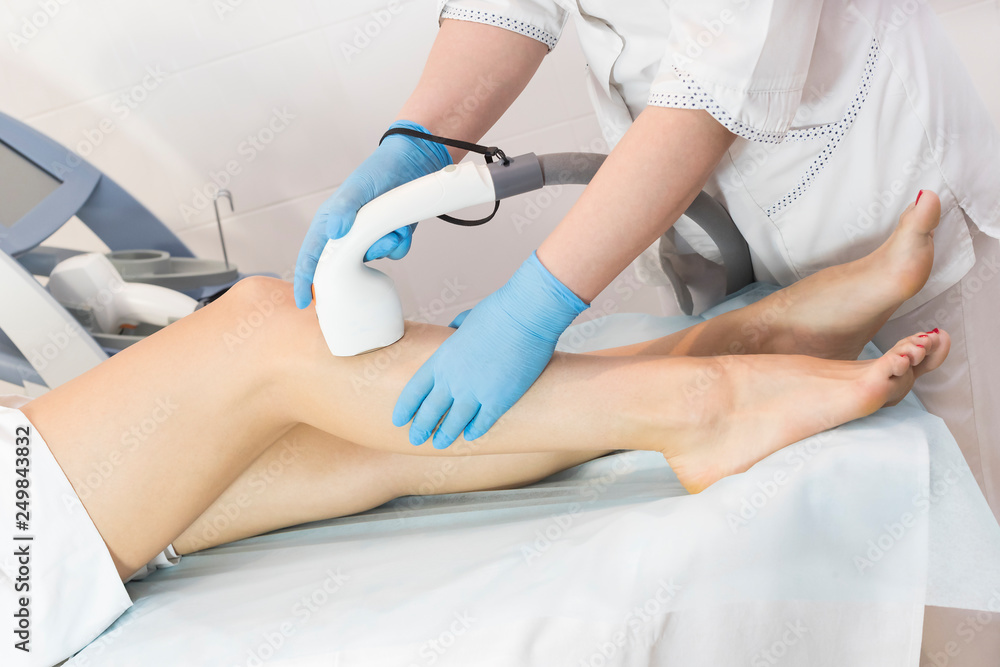 The process of laser depilation of female limbs in the beauty salon.