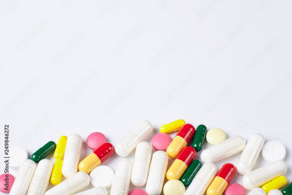 A pile of multicolored pills on white background with copy space. A pile of multicolored pills on white background with copy space.