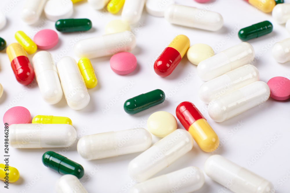 A pile of multicolored pills on white background. Texture. A pile of multicolored pills on white background. Texture.