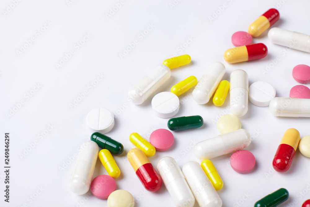A pile of multicolored pills on white background with copy space. A pile of multicolored pills on white background with copy space.