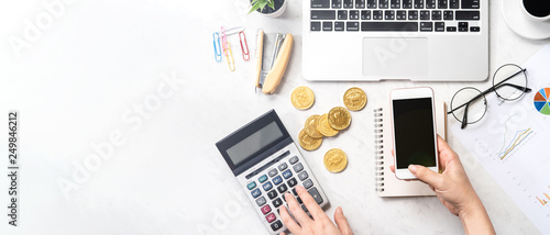 A woman is calculating the fee, profit and doing a payment online on a modern marble office table, mock up, top view, copy space, flat lay, lifestyle photo