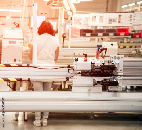 industrial landscape with a worker behind a machine tool, which makes part of wiring for cars at a modern plant in a production workshop