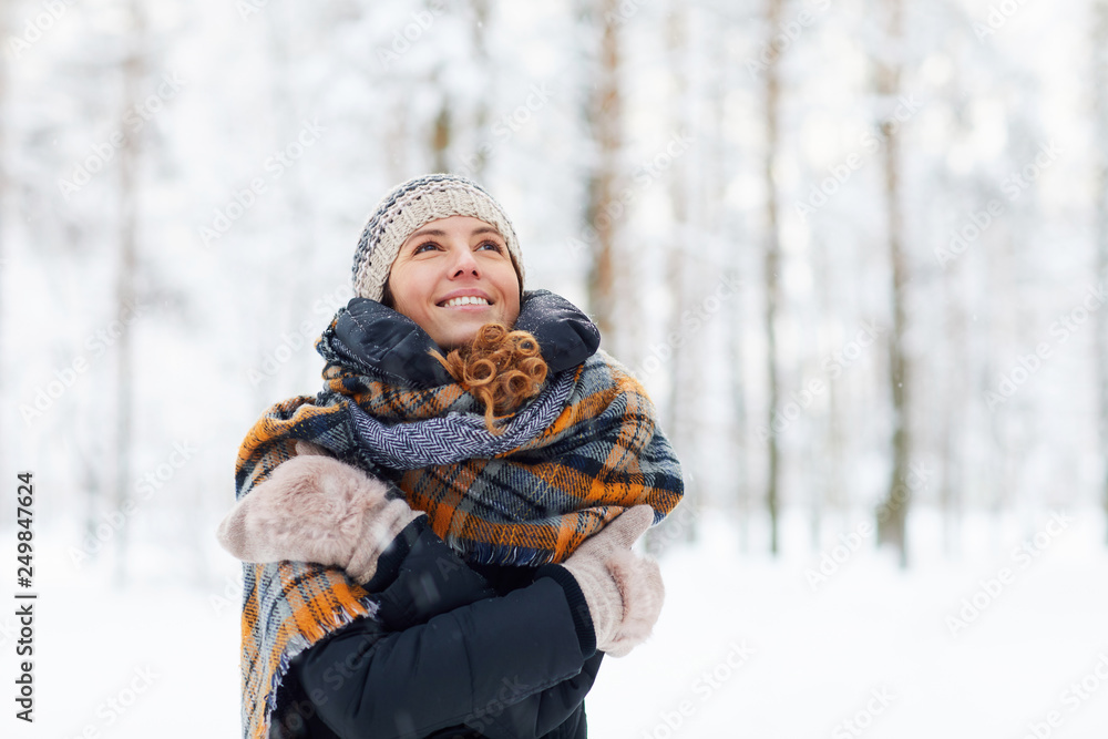 Waist up portrait of happy young woman in winter forest having fun and enjoying snow, copy space