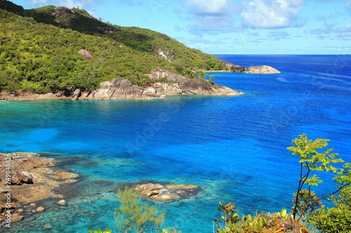 lagoon with clear blue water, tropical greenery and rocks with boulders