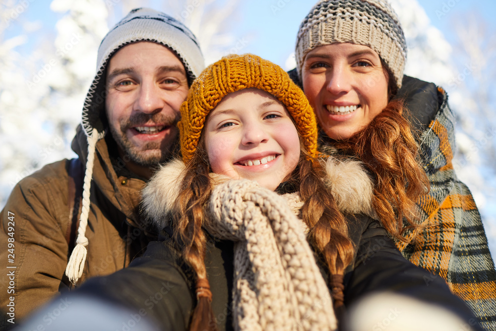 Closeup portrait of happy family posing looking at camera in beautiful winter forest - obrazy, fototapety, plakaty 