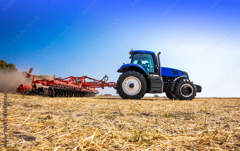 Obraz premium The tractor plows the field, cultivates the soil for sowing grain. The concept of agriculture.