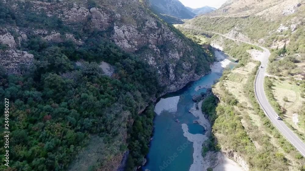 Canyon of the river Moraca in Montenegro with a bird's-eye. Drone flies between the mountains along the road and the river. On two sides, surrounded by rocks of white stone. Canyon of the river Moraca in Montenegro with a bird's-eye. Drone flies between the mountains along the road and the river. On two sides, surrounded by rocks of white stone.