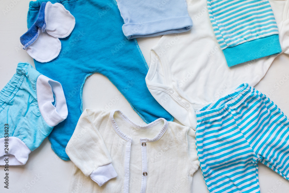 Baby clothes for a newborn boy on a light background. Top view and flat lay. Baby clothes for a newborn boy on a light background. Top view and flat lay.