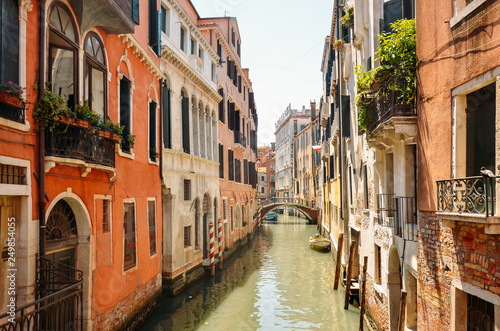 Narrow canal with boat and bridge in Venice, Italy. Architecture and landmark of Venice. Cozy cityscape of Venice