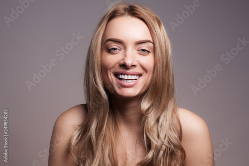 Adult beautiful blond woman with white veneers on the teeth.