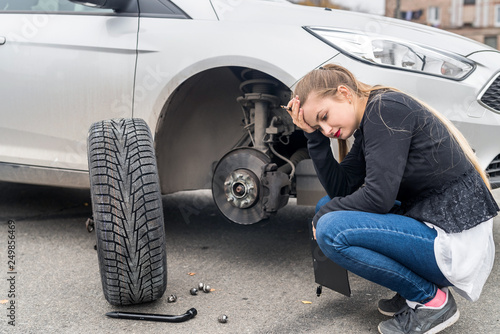 Woman in despair looking at spare wheel for car