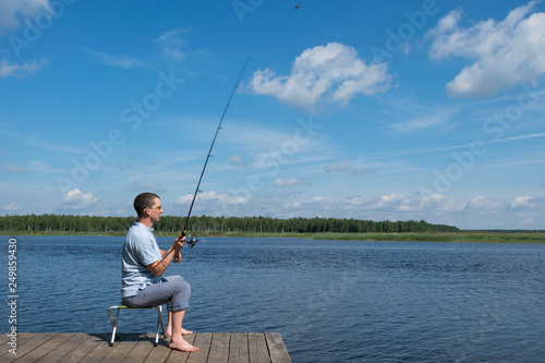 a man sits in a chair on the pier and catches fish on the lake, active recreation