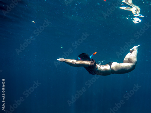 Woman swimming underwater on a blue sea and clear water with good visibility for snorkeling.