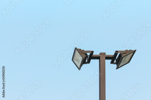 Two spotlight on steel pole and light blue sky background at parking car , off