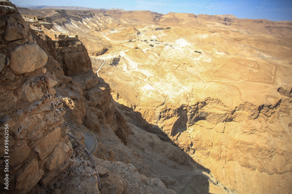 View of the desert from the mountain Masada. Stone and blue sky. Ravines and rifts