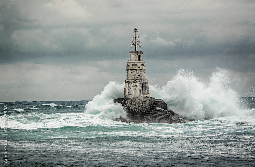 Lighthouse and storm in the sea and large waves that break into the sea light at the port of Ahtopol, Black Sea, Bulgaria