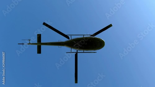 Low angle view of flying black metal rotating blades helicopter on blue sky with white alpha mask channel motion footage.