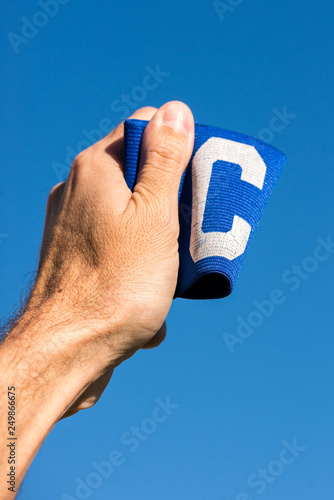 Man's hand holding the soccer Captain armband up to the sky