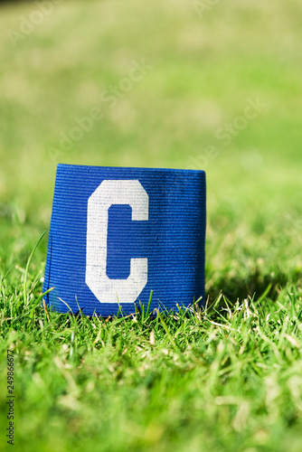 Blue soccer Captain armband, closeup on football pitch grass