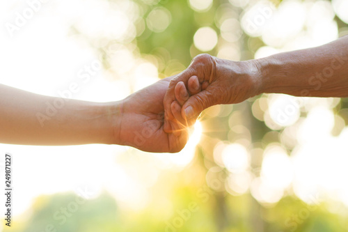 Hand of young man holds Elder person hand with love. metaphor Support, help, nursing home or help for elderly concept. photo
