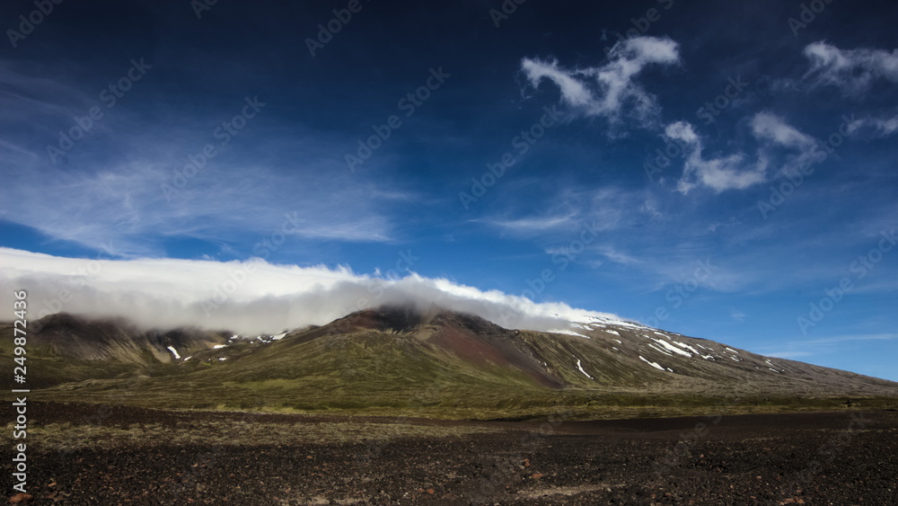 Clouds rolling over Snaefellsjokull glacier on a sunny day on Snaefellsnes peninsula in Western Iceland.