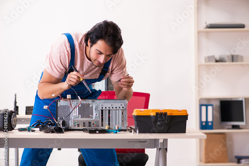Wallpaper Mural Young male contractor repairing computer   Torontodigital.ca