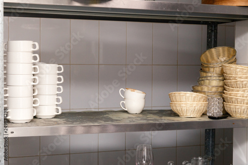 Dirty dishes, wine glasses, plates, cups on metal rack in the restaurant’s kitchen
