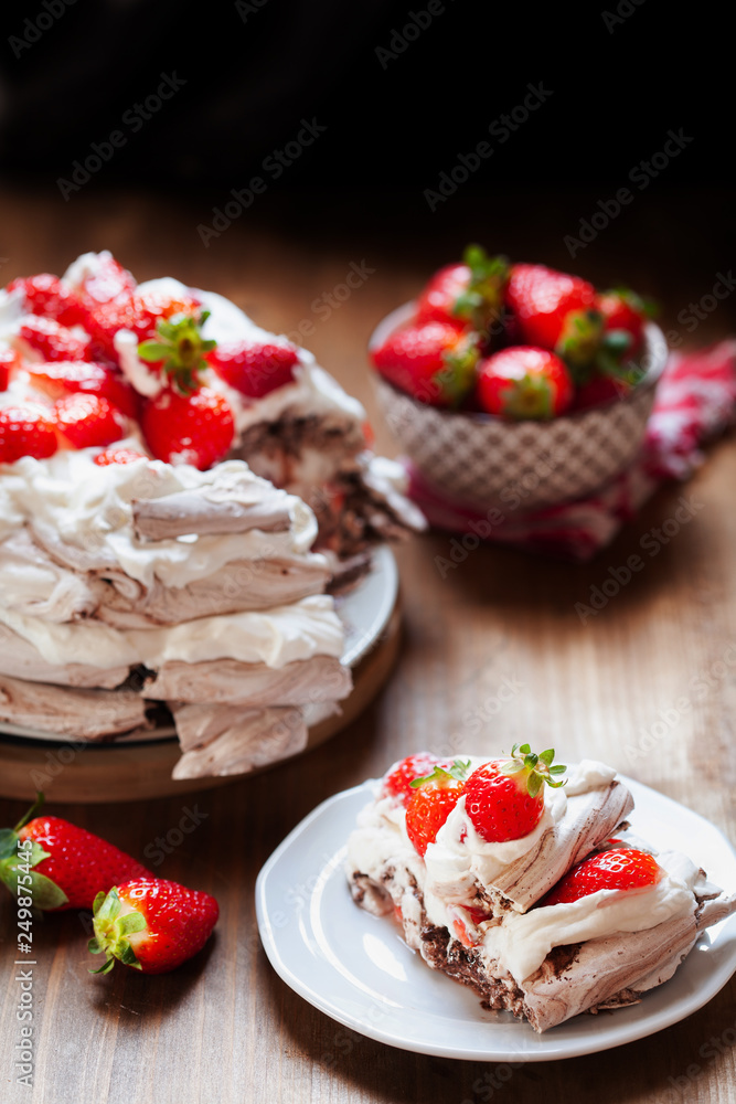 Piece of chocolate meringue cake Pavlova with whipped cream and fresh strawberry Piece of chocolate meringue cake Pavlova with whipped cream and fresh strawberry
