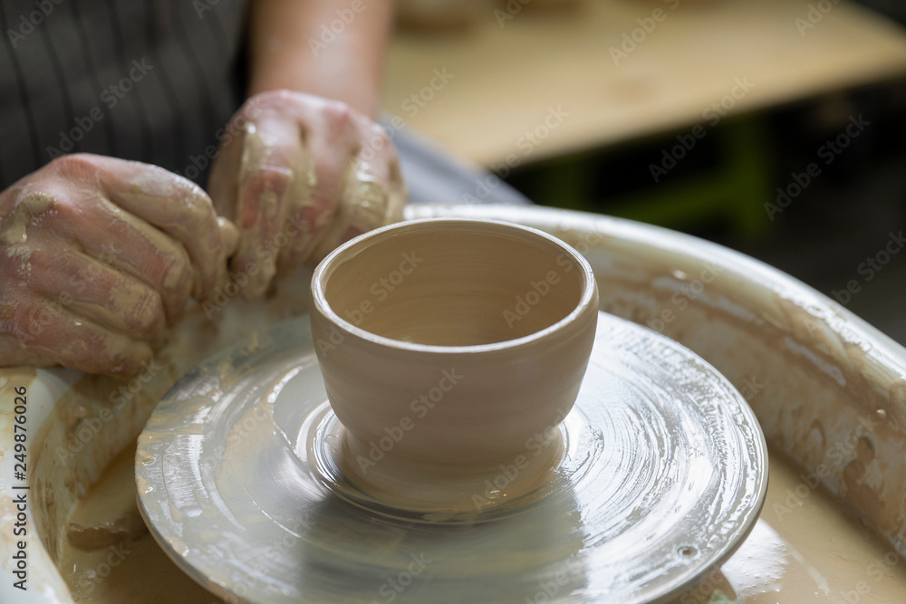 Potter makes the clay product with pottery tools on the potter's wheel Potter makes the clay product with pottery tools on the potter's wheel