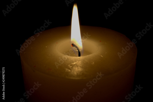 eine leuchtende Flame einer Kerze, eine Kerze spendet Kerzenlicht
