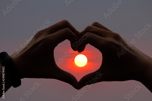 Silhouette of couple hands shaping in heart form at sunset